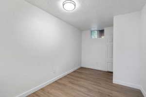 Basement with a textured ceiling and hardwood / wood-style floors