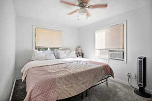 Bedroom with ceiling fan, multiple windows, dark carpet, and ornamental molding