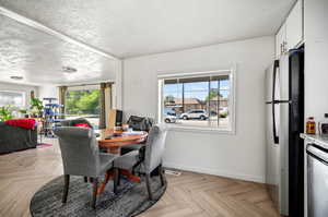 Dining area with a healthy amount of sunlight, a textured ceiling, and light parquet flooring