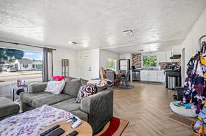 Living room featuring light parquet floors and a textured ceiling