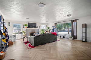 Living room featuring a textured ceiling, a wealth of natural light, and parquet floors