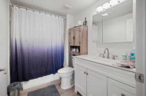 Bathroom featuring wood-type flooring, toilet, vanity, and a textured ceiling