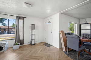 Foyer entrance featuring light parquet flooring and a textured ceiling