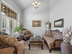 Living room featuring high vaulted ceiling, carpet, and a notable chandelier