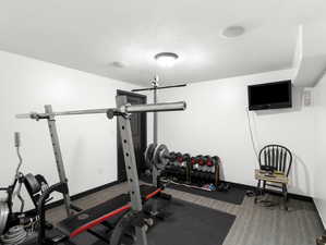 Exercise room featuring a textured ceiling and wood-type flooring