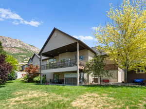 Rear view of property featuring a mountain view, central air condition unit, and a lawn