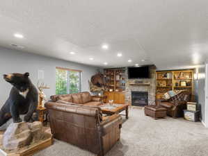 Living room featuring carpet flooring, built in shelves, a fireplace, and a textured ceiling