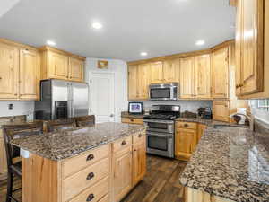 Kitchen with stainless steel appliances, sink, a kitchen island, a kitchen breakfast bar, and dark wood-type flooring