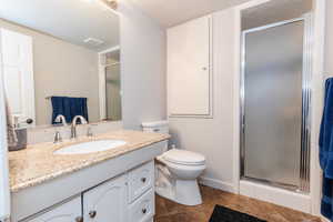 Bathroom featuring vanity, walk in shower, tile patterned flooring, and toilet