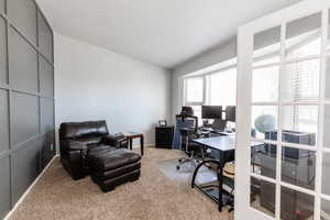 Carpeted home office featuring vaulted ceiling