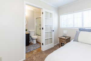 Bedroom featuring ensuite bathroom, tile patterned flooring, and crown molding