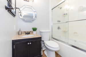 Full bathroom featuring vanity, combined bath / shower with glass door, toilet, and tile patterned flooring