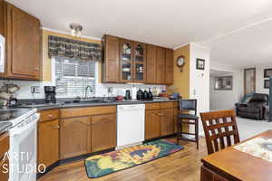 Kitchen featuring sink, tasteful backsplash, light wood-type flooring, and white appliances