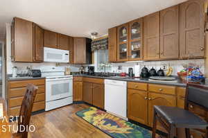 Kitchen with hardwood / wood-style flooring, backsplash, white appliances, and sink