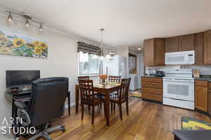 Kitchen with a chandelier, dark hardwood / wood-style flooring, white appliances, ornamental molding, and track lighting