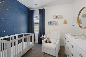 Bedroom with dark colored carpet and a crib