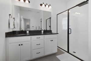 Bathroom featuring a shower with door, tile patterned flooring, and double sink vanity