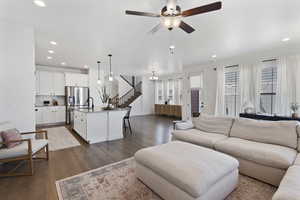 Living room with sink, ceiling fan with notable chandelier, and dark hardwood / wood-style floors