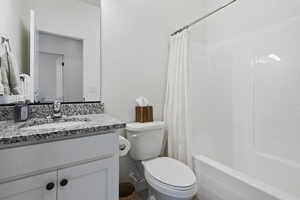 Full bathroom featuring shower / bath combo with shower curtain, vanity, and toilet