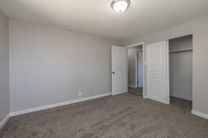 Unfurnished bedroom featuring dark colored carpet, a closet, and a textured ceiling