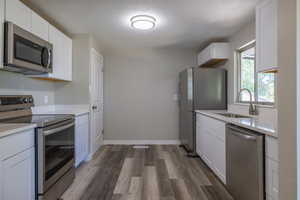 Kitchen featuring sink, appliances with stainless steel finishes, dark hardwood / wood-style floors, and white cabinetry