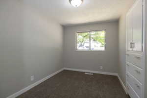 Carpeted empty room featuring a textured ceiling