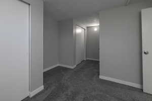 Empty room featuring dark carpet and a textured ceiling