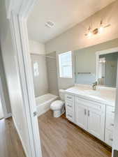 Full bathroom with wood-type flooring, vanity, toilet, and tiled shower / bath combo