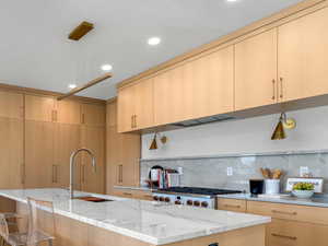 Kitchen featuring white oak cabinetry and island with a sink.