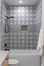 Full bathroom with vanity, tiled shower / bath combo, and toilet