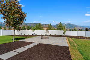 Fully fenced backyard with a mountain view, a patio area, and a fire pit