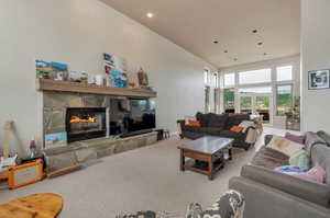 Living room with carpet floors, a fireplace, and a high ceiling