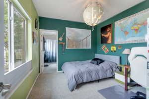 Carpeted bedroom with a notable chandelier and ensuite bathroom