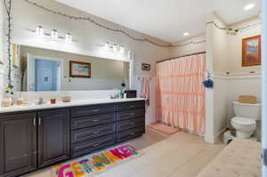 Bathroom featuring dual vanity, toilet, and tile patterned flooring