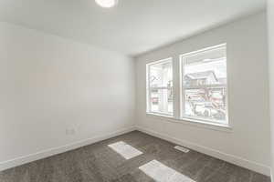 Unfurnished room featuring a textured ceiling and dark colored carpet