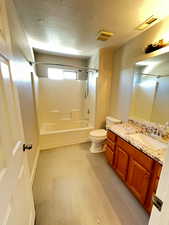 Full bathroom with toilet, tiled shower / bath combo, and vanity