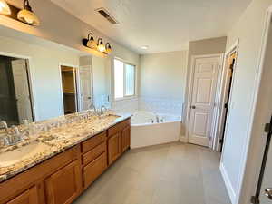 Bathroom featuring dual vanity, tile patterned flooring, and a tub