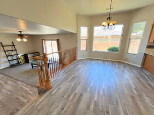 Spare room featuring ceiling fan with notable chandelier and hardwood / wood-style floors