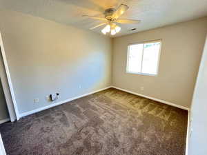 Spare room with dark colored carpet and ceiling fan