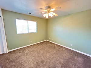 Carpeted spare room featuring ceiling fan