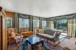 Living room featuring a textured ceiling, carpet floors, and an inviting chandelier