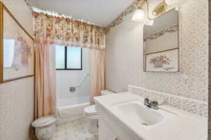 Full bathroom with tile patterned floors, shower / bath combo, toilet, and vanity