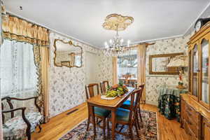 Dining area with a notable chandelier, hardwood / wood-style floors, and ornamental molding