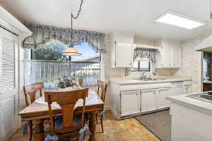 Kitchen with sink, white cabinetry, pendant lighting, and light tile patterned flooring