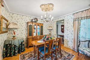 Dining room featuring light hardwood / wood-style floors, a notable chandelier, and ornamental molding