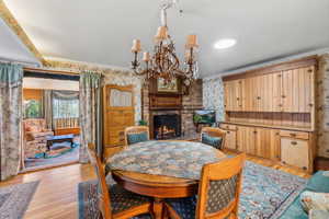 Dining space with light hardwood / wood-style floors, ornamental molding, a fireplace, and brick wall