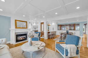 Living room with light hardwood / wood-style flooring, ornamental molding, and coffered ceiling