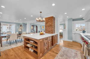 Kitchen featuring an inviting chandelier, light hardwood / wood-style floors, light stone countertops, hanging light fixtures, and ornamental molding