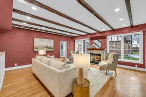 Living room featuring a fireplace, beamed ceiling, and light hardwood / wood-style flooring