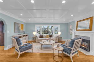 Living room featuring a tile fireplace, light hardwood / wood-style flooring, and coffered ceiling